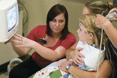 Technician, patient and family watching EEG video monitor