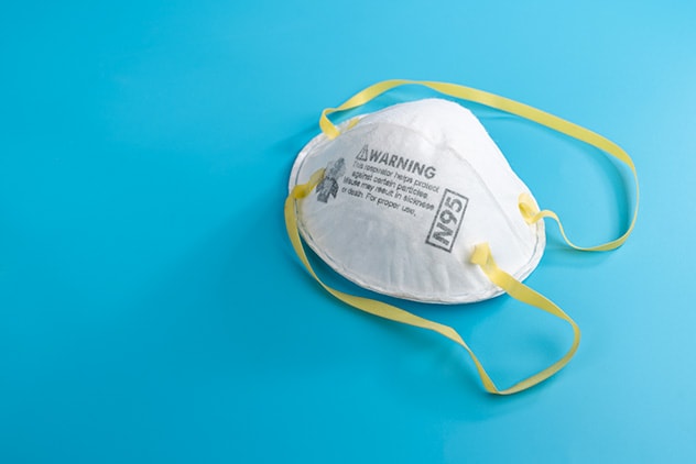 A white N95 mask with yellow straps