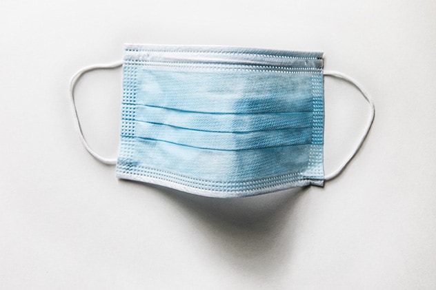 A blue surgical mask with white ear loops