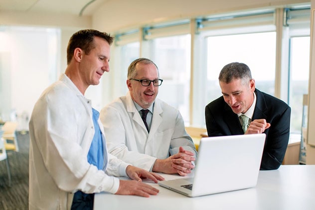 Colorectal surgeons review research results together on a laptop.