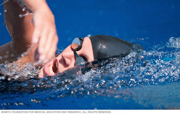 A lap swimmer in goggles takes a breath.