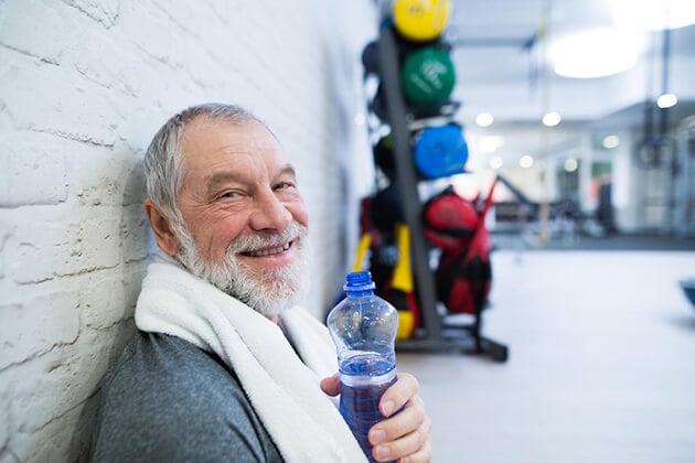 Un hombre sonríe mientras sostiene una botella de agua en una sesión de terapia.
