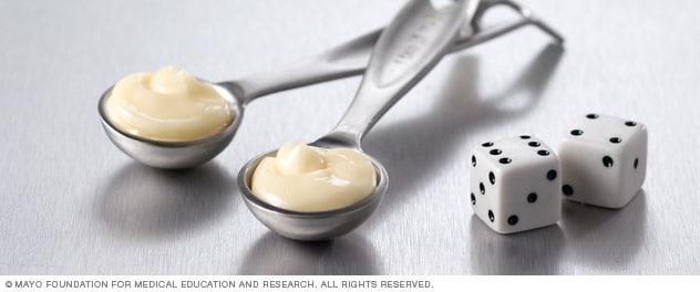 Two teaspoons of mayonnaise next to dice.