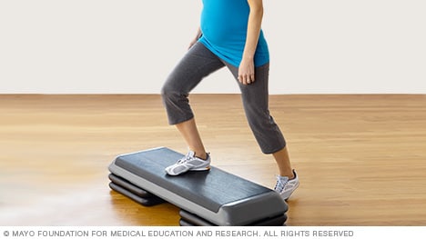 Persona embarazada haciendo un ejercicio con escalón