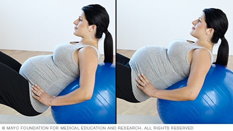 Persona embarazada haciendo una inclinación pélvica con una pelota de gimnasia.