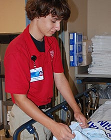 صورة لمتطوع مراهق في Mayo Clinic (مايو كلينك) يطوي الشراشف