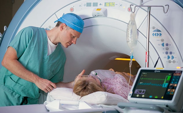 Un técnico anima a una paciente en el equipo de resonancia magnética