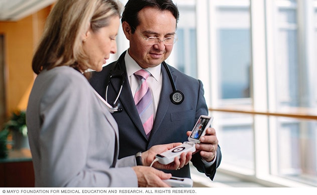 Two doctors consult over a handheld cardiac monitoring device.