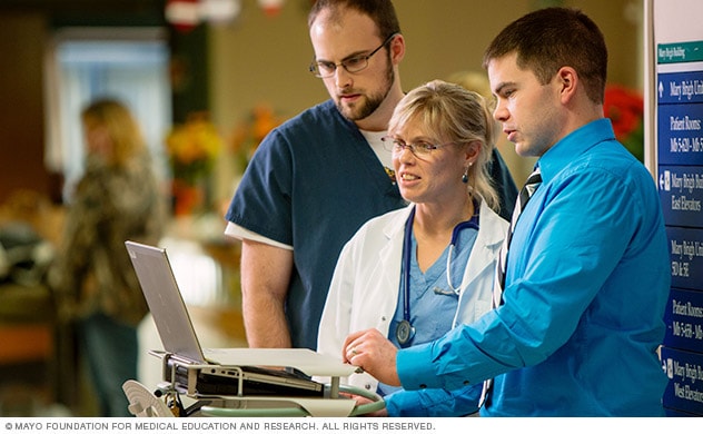 A group of people in a discussion looking at a laptop
