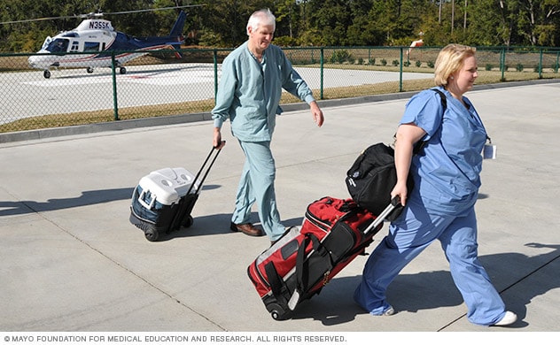 اثنان من أعضاء طاقم Mayo Clinic (مايو كلينك) يمشيان وهما حاملان مبردات من هيلوكوبتر.