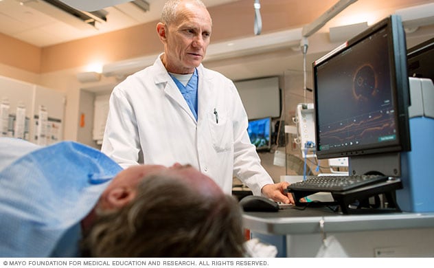 Un médico se encuentra junto a una persona y realiza un estudio de diagnóstico por imágenes