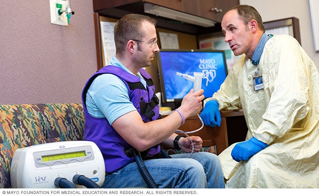 A respiratory therapist with a person wearing a vest for vest therapy