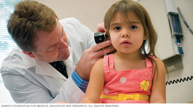 一位医生正给前来家庭医学诊所就诊的女孩检查耳朵。