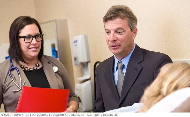 Dos miembros de un equipo de atención médica de Mayo Clinic en consulta con un paciente.