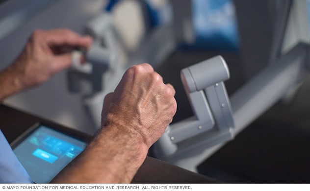 A surgeon sits at a remote console and conducts robot-assisted heart surgery.