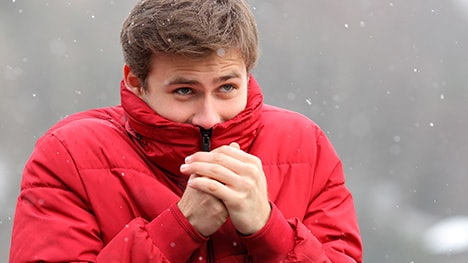 Man zipping jacket as snow falls