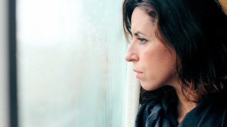 Woman with bleak expression gazing at gray skies