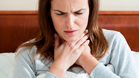 Sick woman holding throat with pained expression
