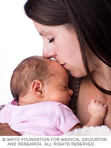 A woman kisses her newborn baby.