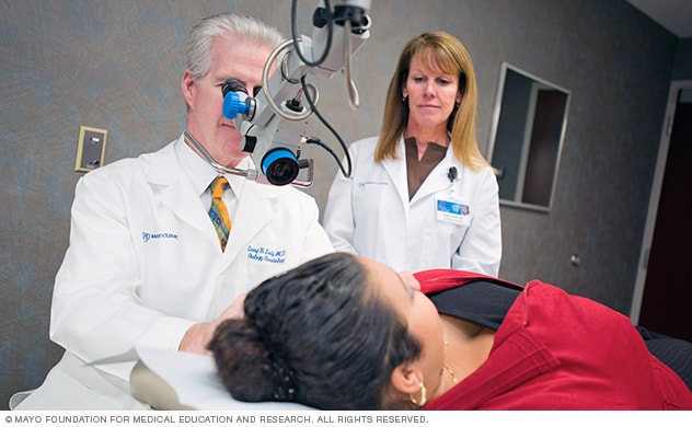 A doctor who specializes in the diagnosis and treatment of ear, nose and throat conditions (otorhinolaryngologist) examines a patient.