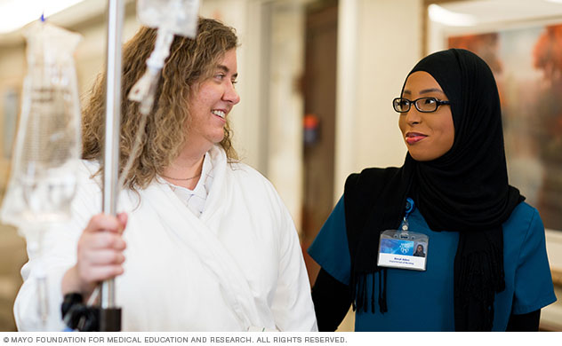 A patient and Mayo Clinic staff person walk down a Suites at Saint Marys hallway.