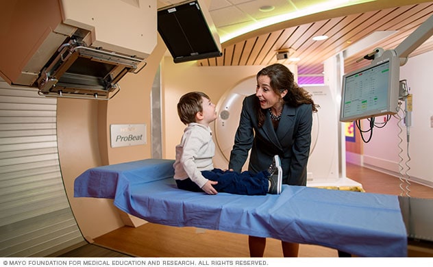 Proton beam specialist cares for a child in a treatment room.