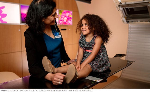 质子束治疗科主任在治疗室内治疗一名儿童。