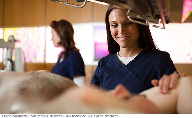 Proton beam specialists cares for a patient in a treatment room.