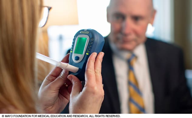 一名戒烟咨询师正使用一氧化碳筛查装置对患者进行监测。