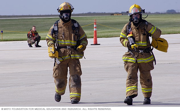Safety workers in fire gear move across a tarmac.