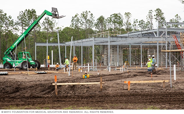 A construction site’s open field with workers and scaffolding.