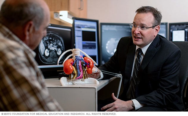 Un radiólogo utiliza un modelo 3D para ayudar a un hombre a entender su diagnóstico.