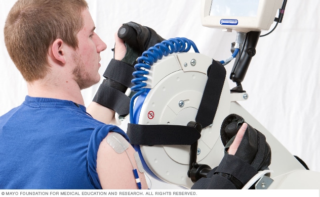 A young man uses a machine during a spine injury rehabilitation therapy session.