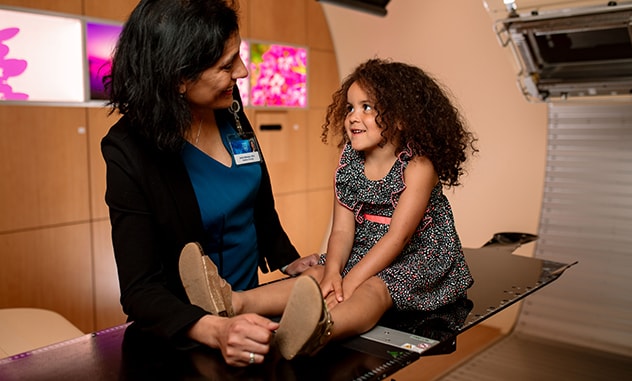 Radiation oncologist talks with pediatric cancer patient.