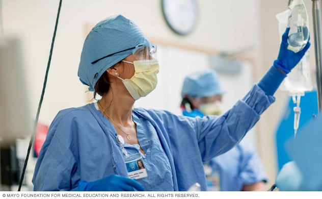 A nurse checks on an intravenous drip.