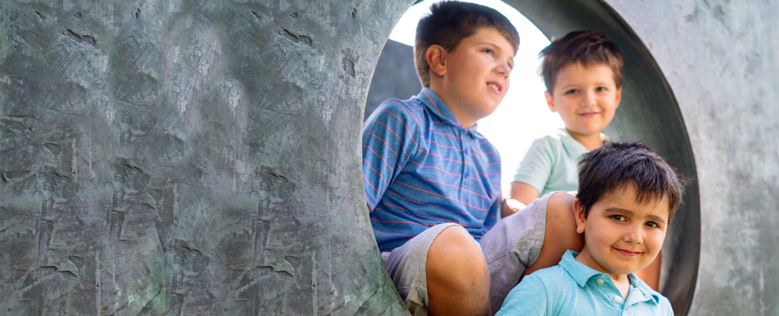 Three kids on a sculpture outdoors