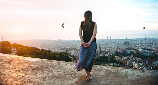 Una mujer descalza está de pie en un mirador sobre Barcelona, España.