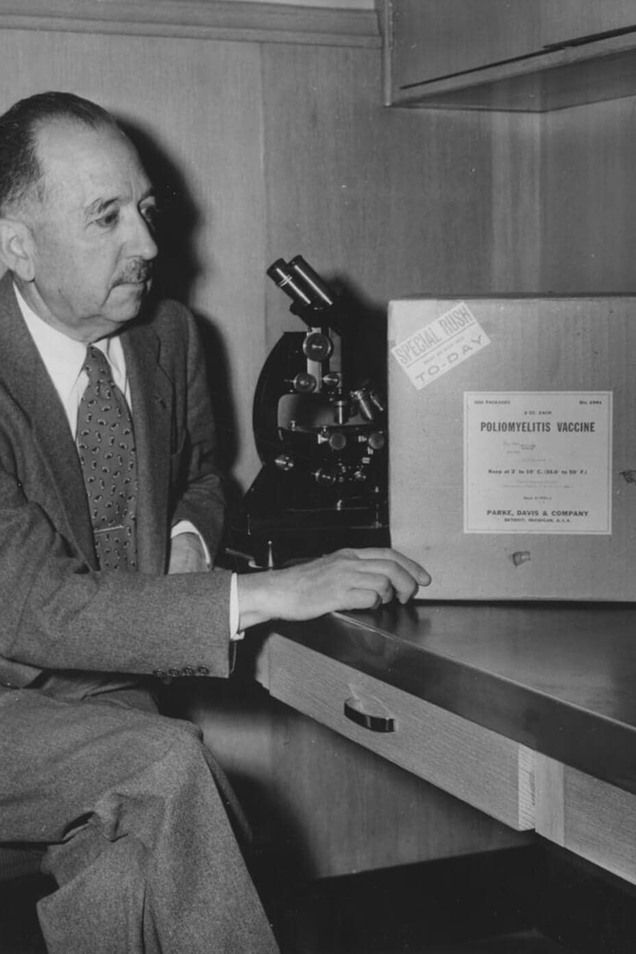 الدكتور توماس ماجاث جالسًا إلى مكتب وينظر إلى الشحنة الأولى من لقاح شلل الأطفال في مايو كلينك في عام 1955