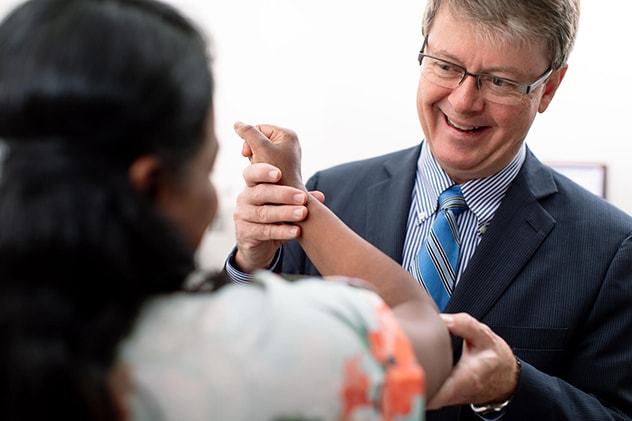 A Mayo Clinic orthopedic surgeon at a patient in consultation during elbow evaluation.