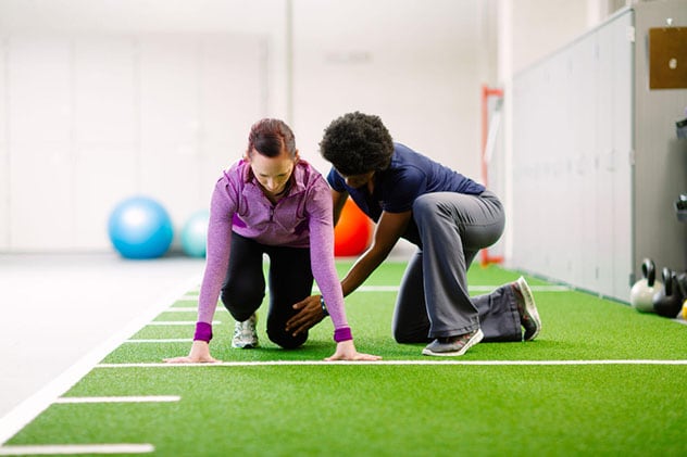 A person in recovery does leg stretching exercises with a Mayo Clinic therapist.