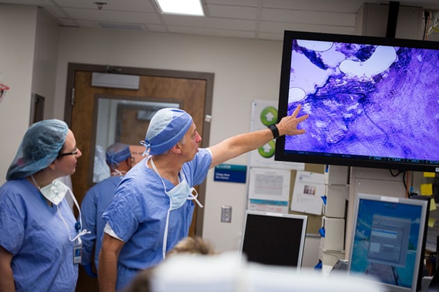 جراحون يراجعون صور مقطع مجمد أثناء عملية جراحية.