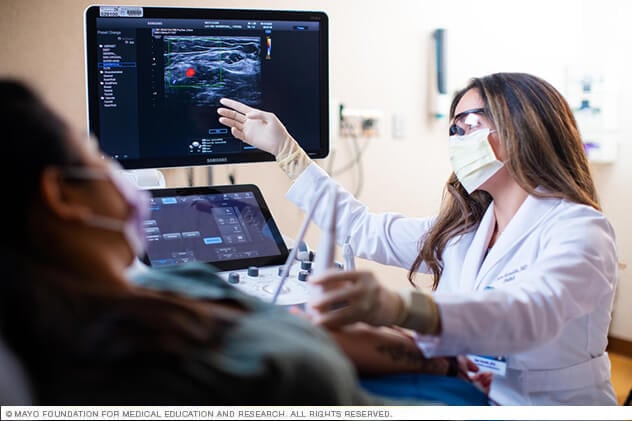 A Biotherapeutics and Advanced Procedures Clinic physician consults a scan display with a patient.