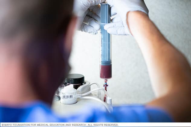 A technician securely transfers whole blood into a centrifuge for plasma separation.