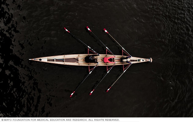 Three rowers pull together on water.