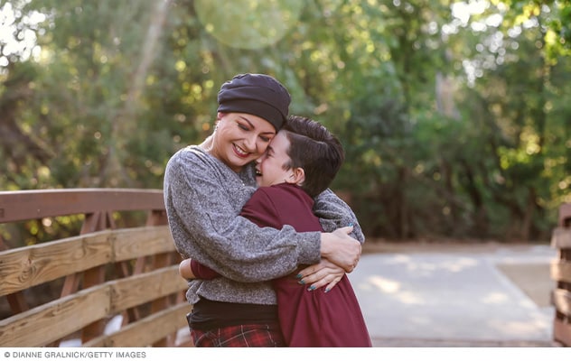 People hug on a woodland path.