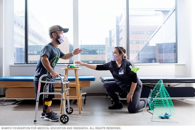 A man using a walker plays a toss game with a therapist.