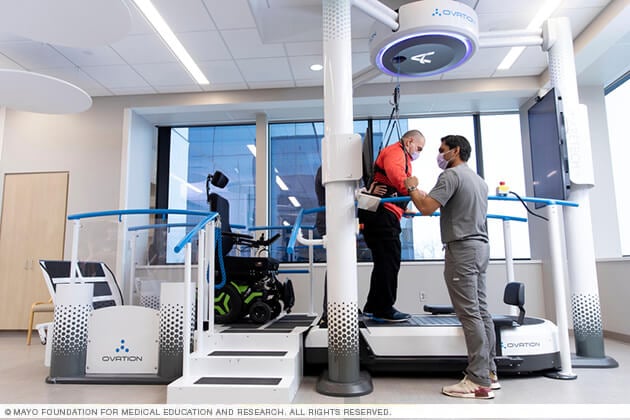 A man works on a specialized balance apparatus with a physical therapist.