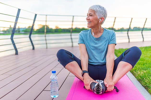 A woman performs a stretching exercise near a track.