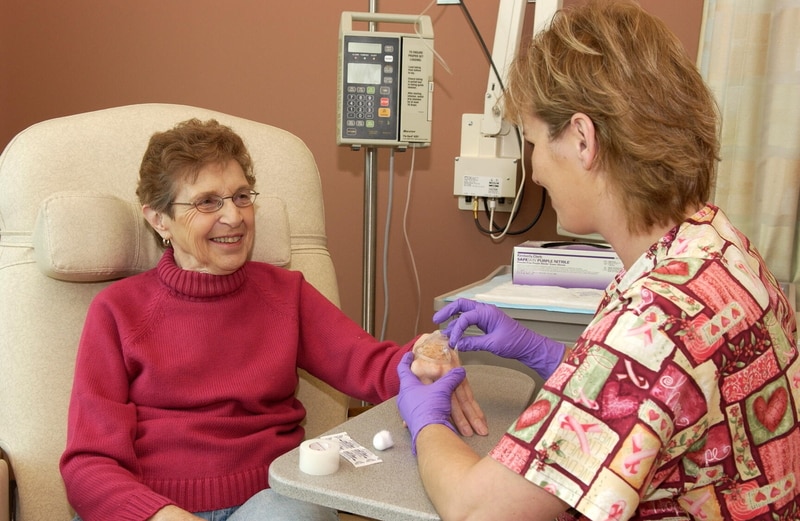 A woman sits in a recliner as she is prepared for a blood infusion.