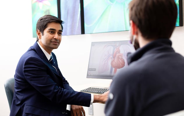 A doctor reviews a heart image on the computer with a patient.